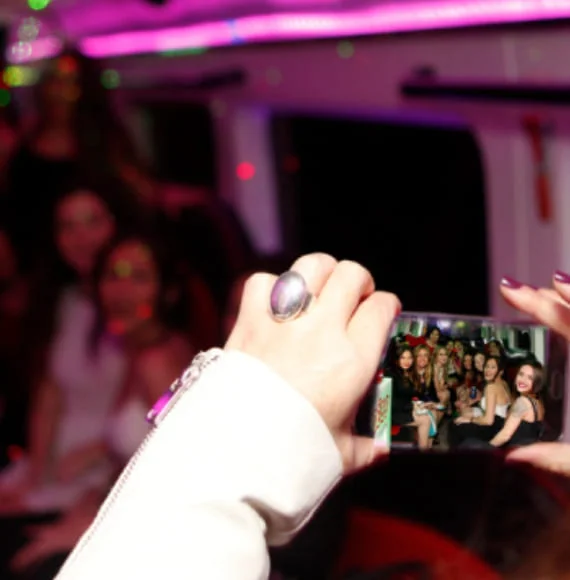Chica capturando un momento especial de sus amigas en una fiesta dentro del Limobus – Mini Discos Limusina Barcelona.