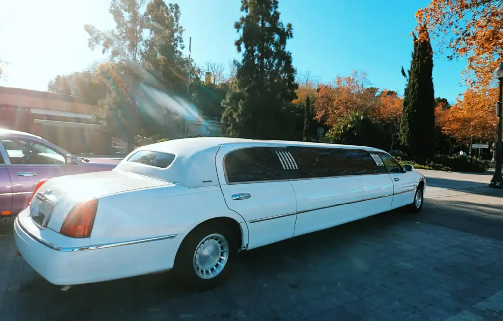 Clásica limusina Lincoln americana blanca con paisaje de fondo, aparcada en un entorno bonito
